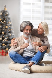 Photo of Happy mature couple with glasses of champagne celebrating Christmas at home