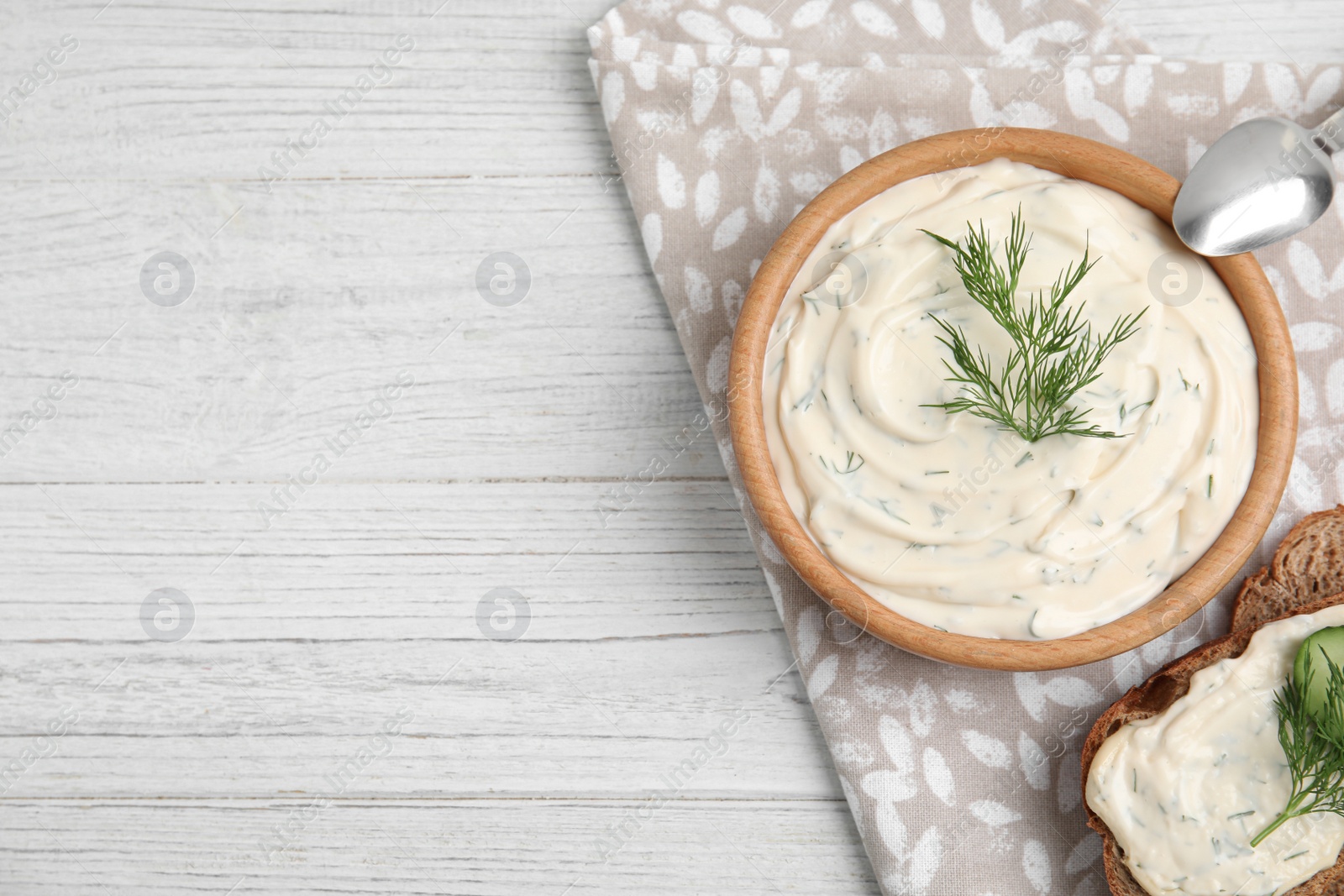 Photo of Tasty creamy dill sauce and sandwich on white wooden table, flat lay. Space for text