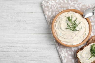 Photo of Tasty creamy dill sauce and sandwich on white wooden table, flat lay. Space for text