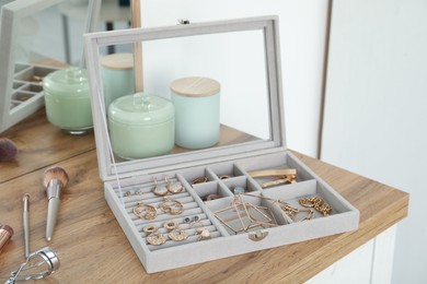 Photo of Elegant jewelry box with beautiful bijouterie, cosmetics and candles on wooden table