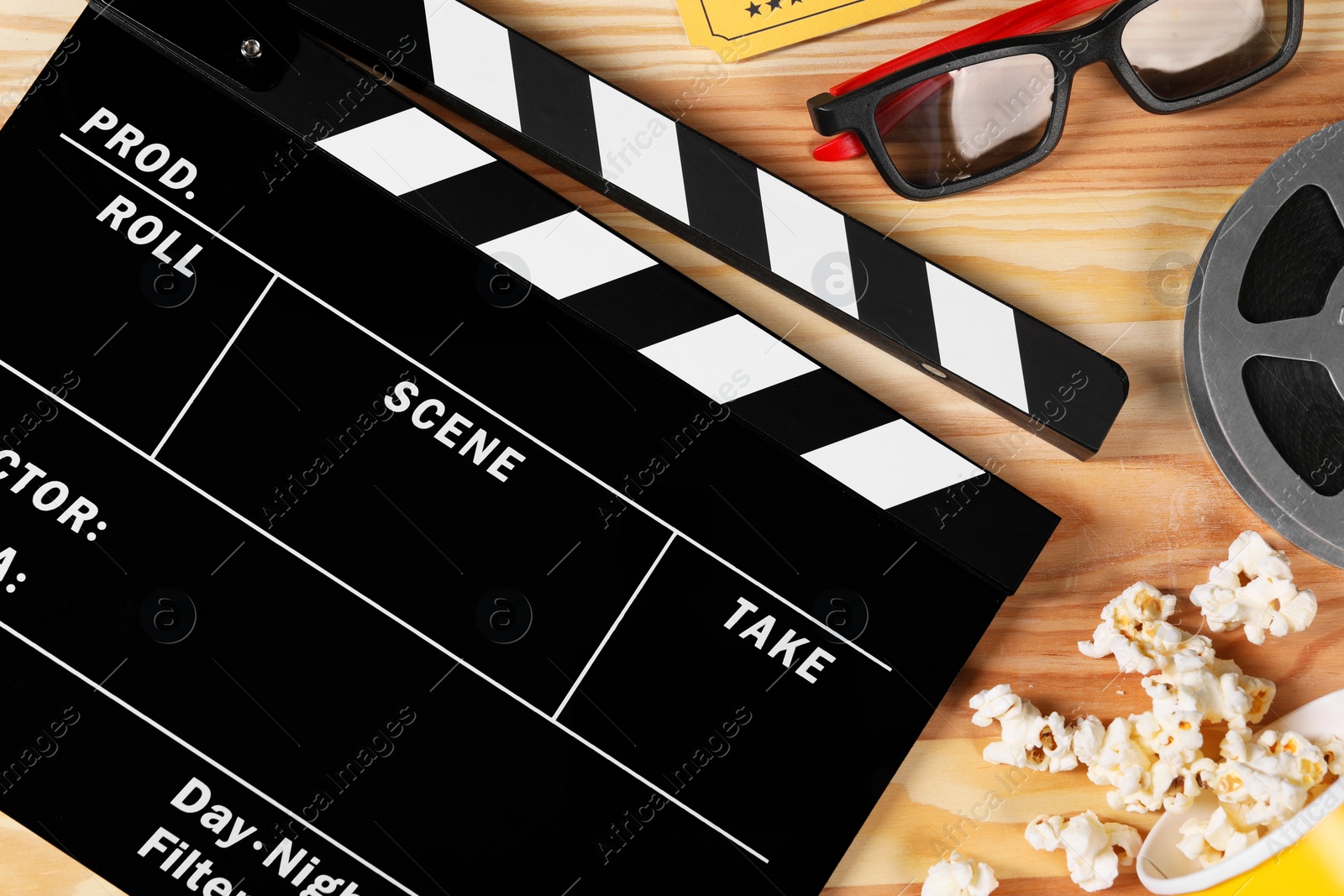 Photo of Clapperboard, 3D glasses, popcorn and film reel on wooden table, flat lay