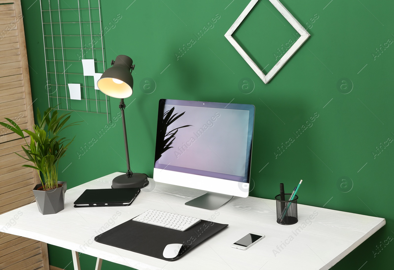 Photo of Stylish workplace with modern computer near color wall. Space for text