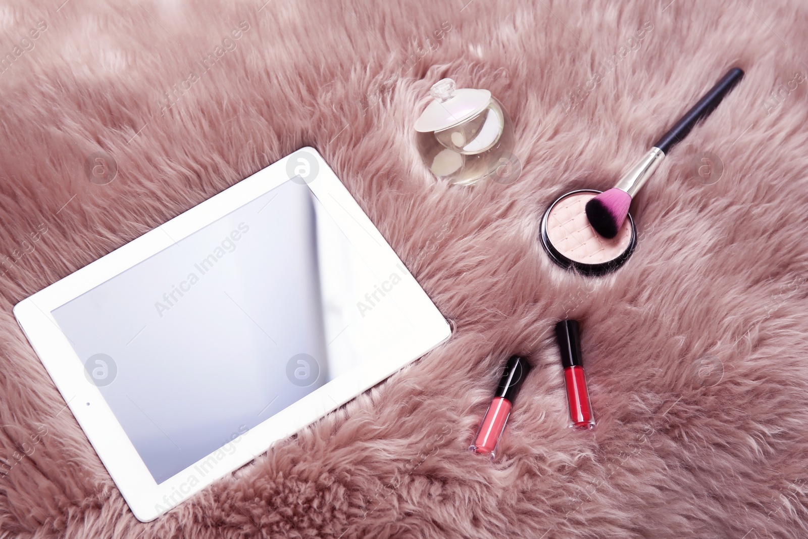 Photo of Composition with tablet and makeup products for woman on fur