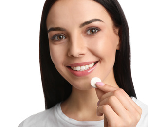 Young woman taking vitamin pill on white background, closeup