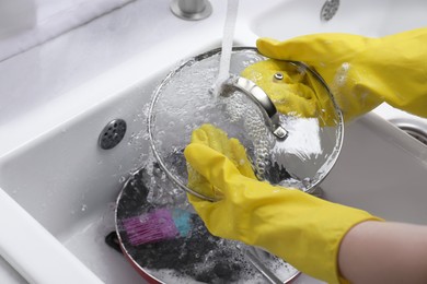Woman washing dirty dishes in kitchen sink, closeup