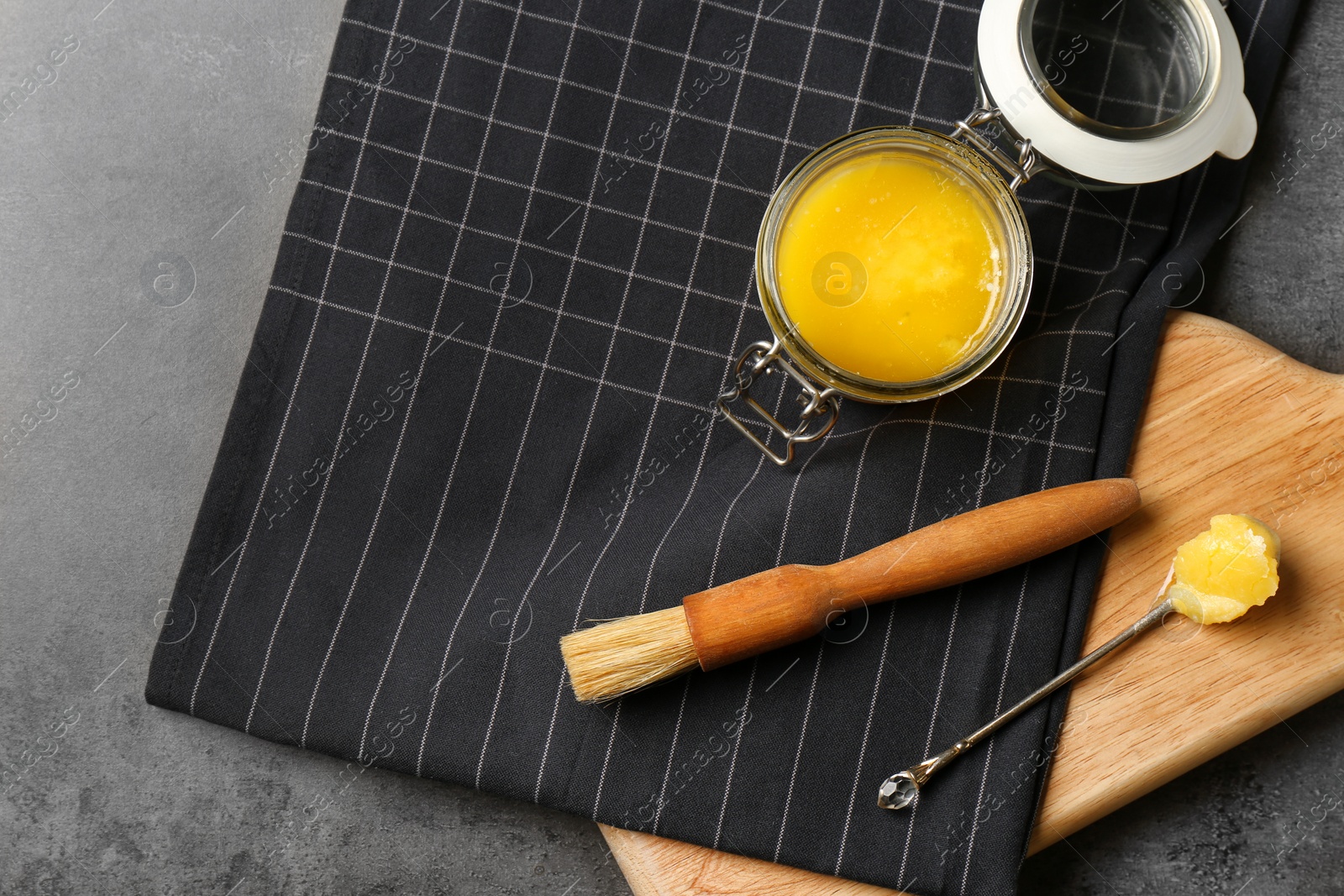 Photo of Flat lay composition with clarified butter and basting brush on grey background. Space for text