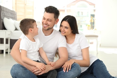 Happy parents and their son sitting together on floor at home. Family time