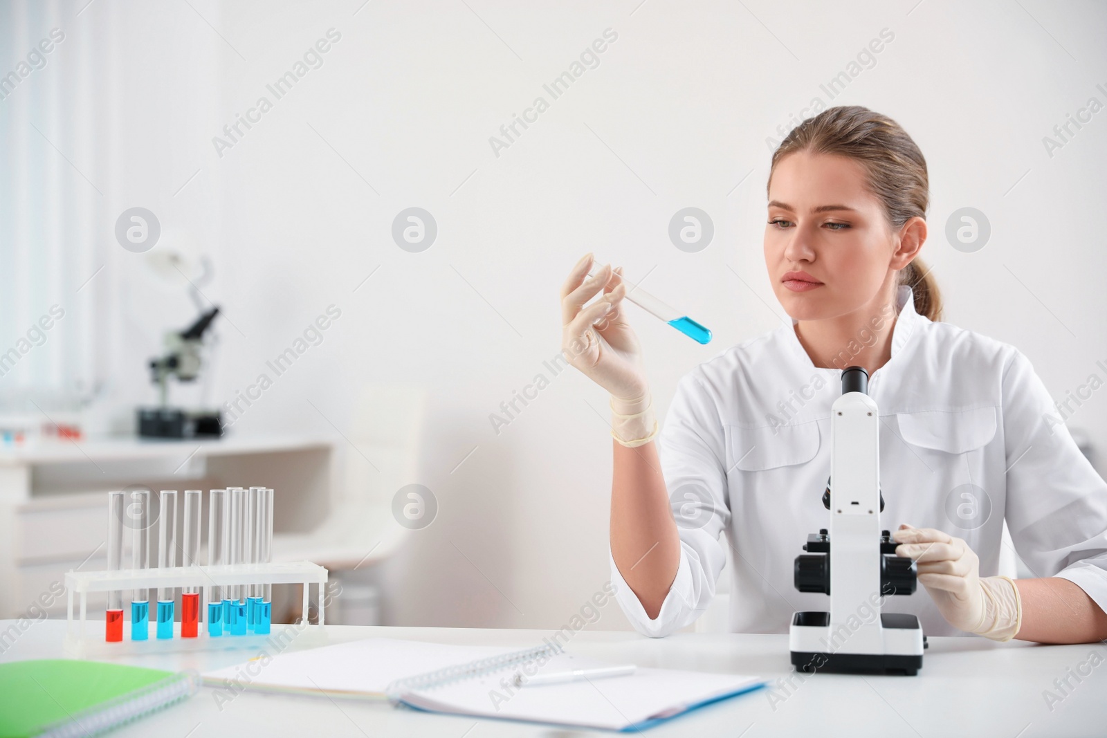 Photo of Scientist with test tube and microscope at table. Medical research