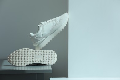 Photo of Stylish presentation of trendy sneakers on color background. Space for text