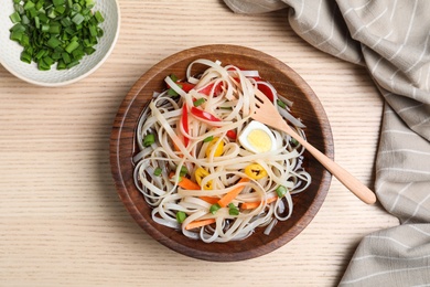 Bowl of noodles with broth, vegetables and egg on wooden background, top view