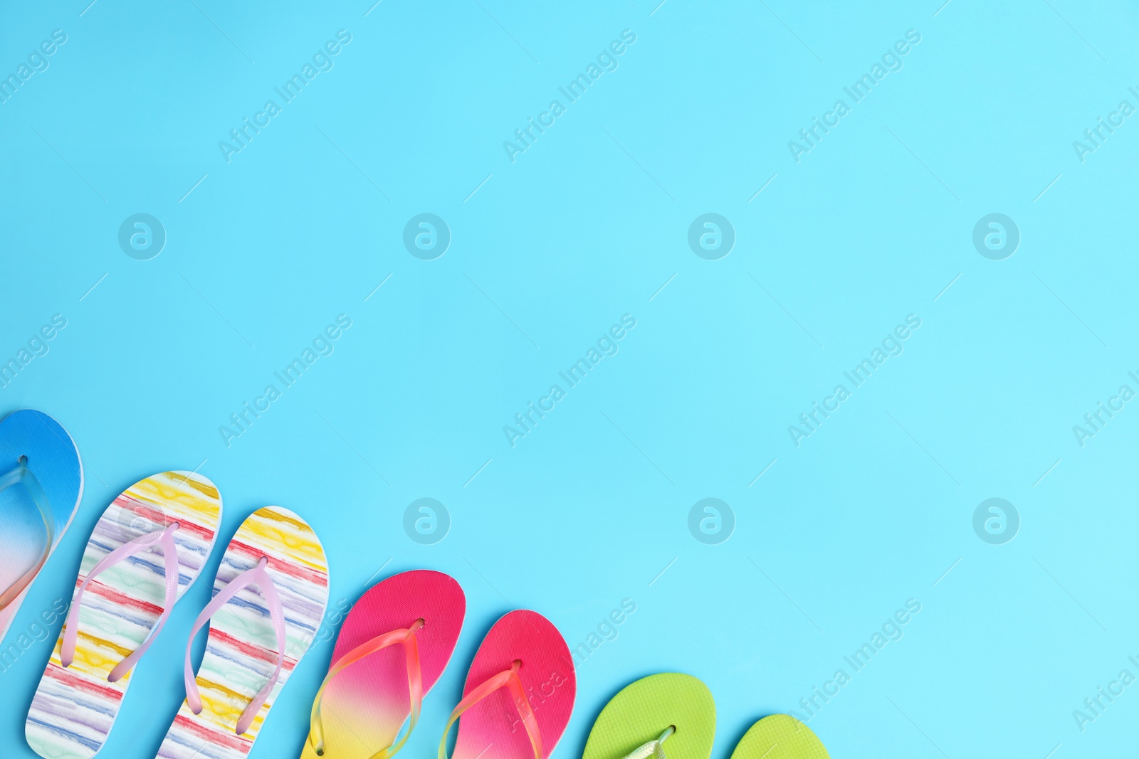 Photo of Different flip flops and space for text on blue background, flat lay. Summer beach accessories