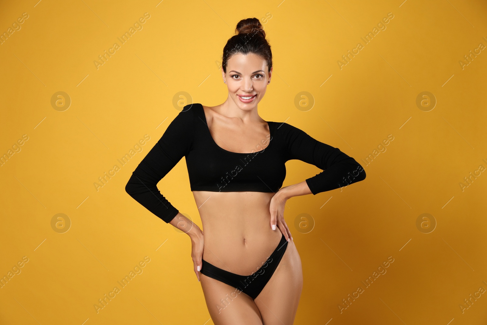 Photo of Beautiful woman in black sexy panties on yellow background