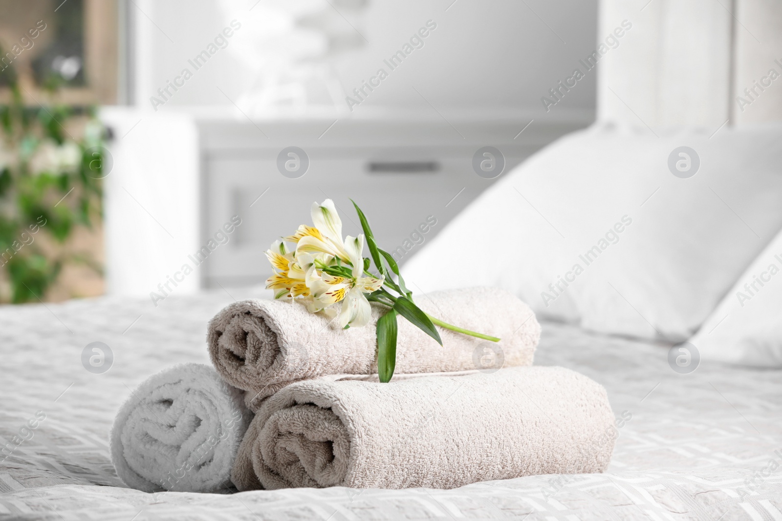 Photo of Terry towels with beautiful flowers on bed indoors, space for text