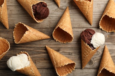 Ice cream scoops in wafer cones on wooden table, flat lay