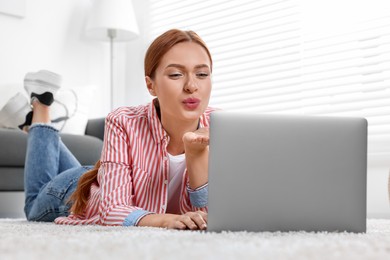 Woman blowing kiss during video chat via laptop at home. Long-distance relationship