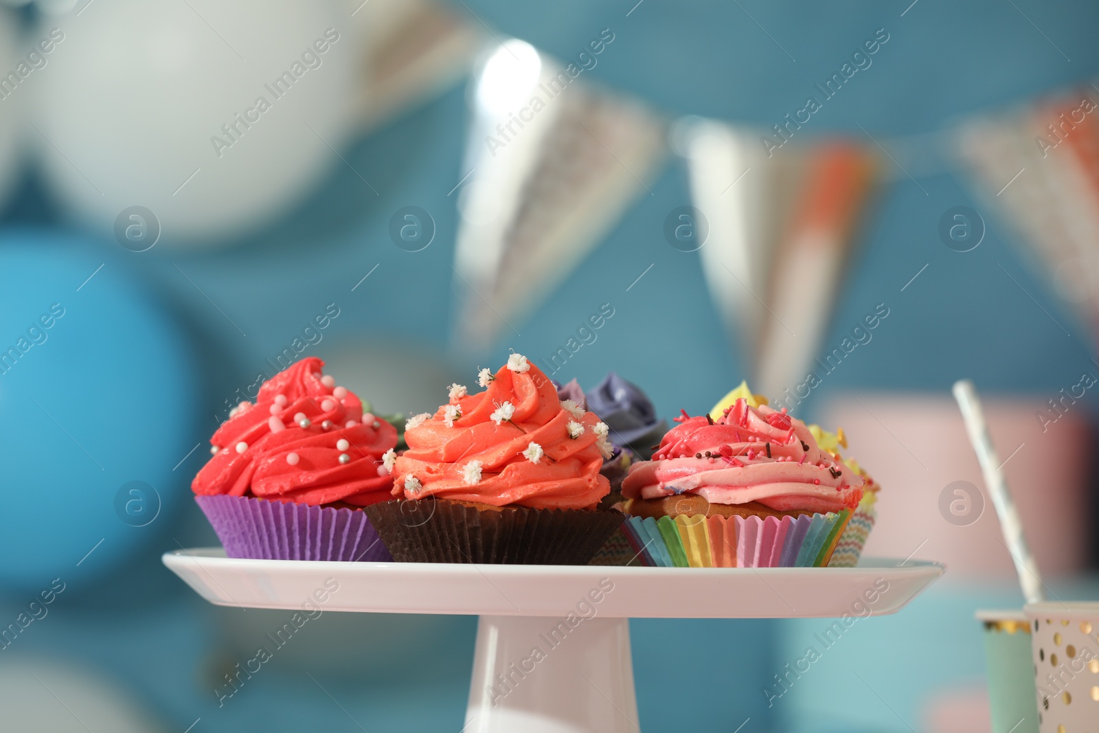 Photo of Different colorful cupcakes and party accessories on pink table