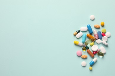Photo of Pile of different pills on mint background, flat lay. Space for text