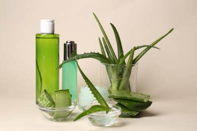 Cosmetic products and fresh aloe on beige background