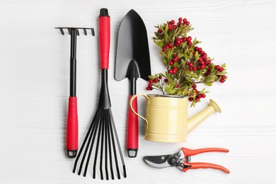 Photo of Flat lay composition with watering can and gardening tools on white wooden table