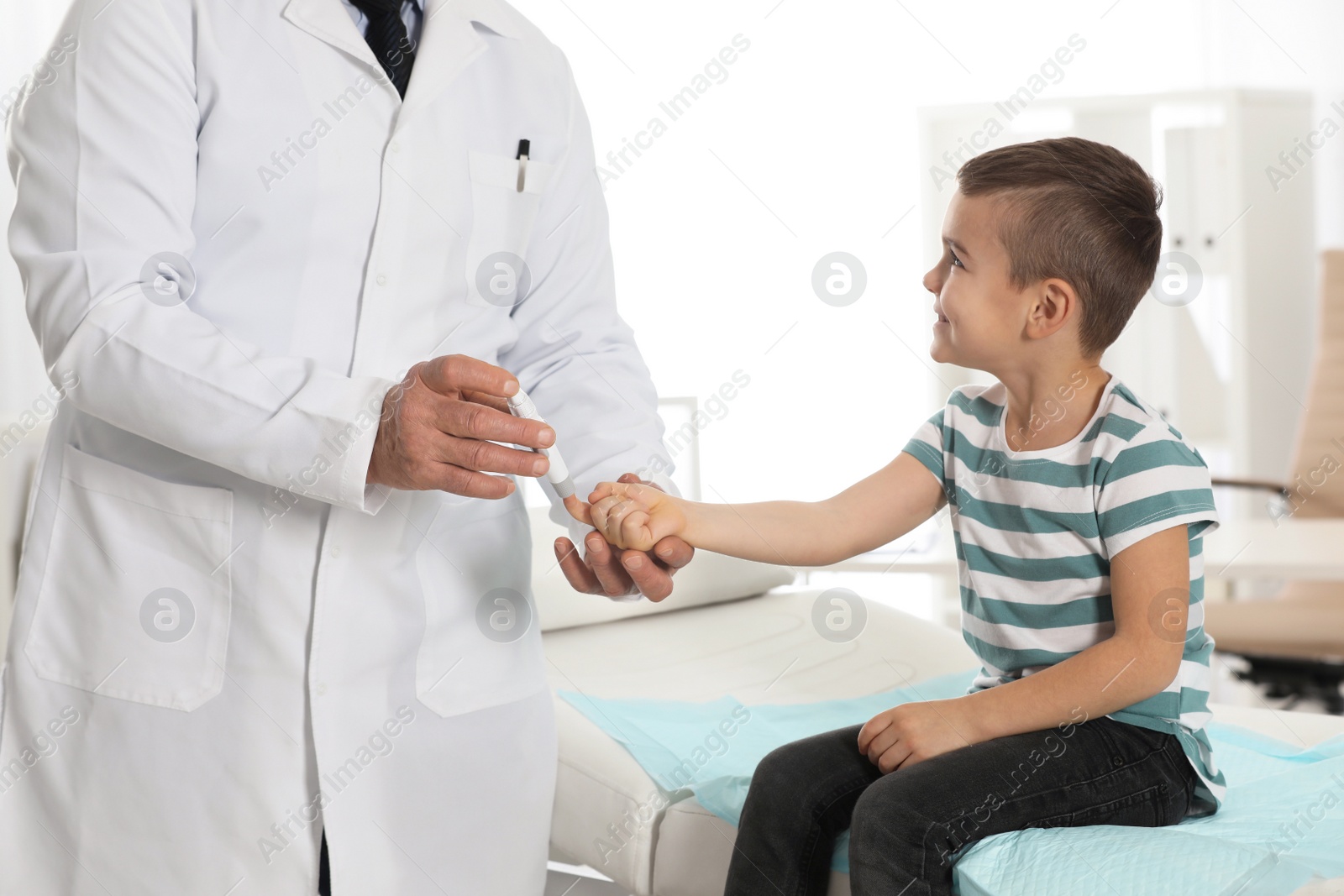 Photo of Little patient and doctor with lancet pen in hospital. Diabetes control