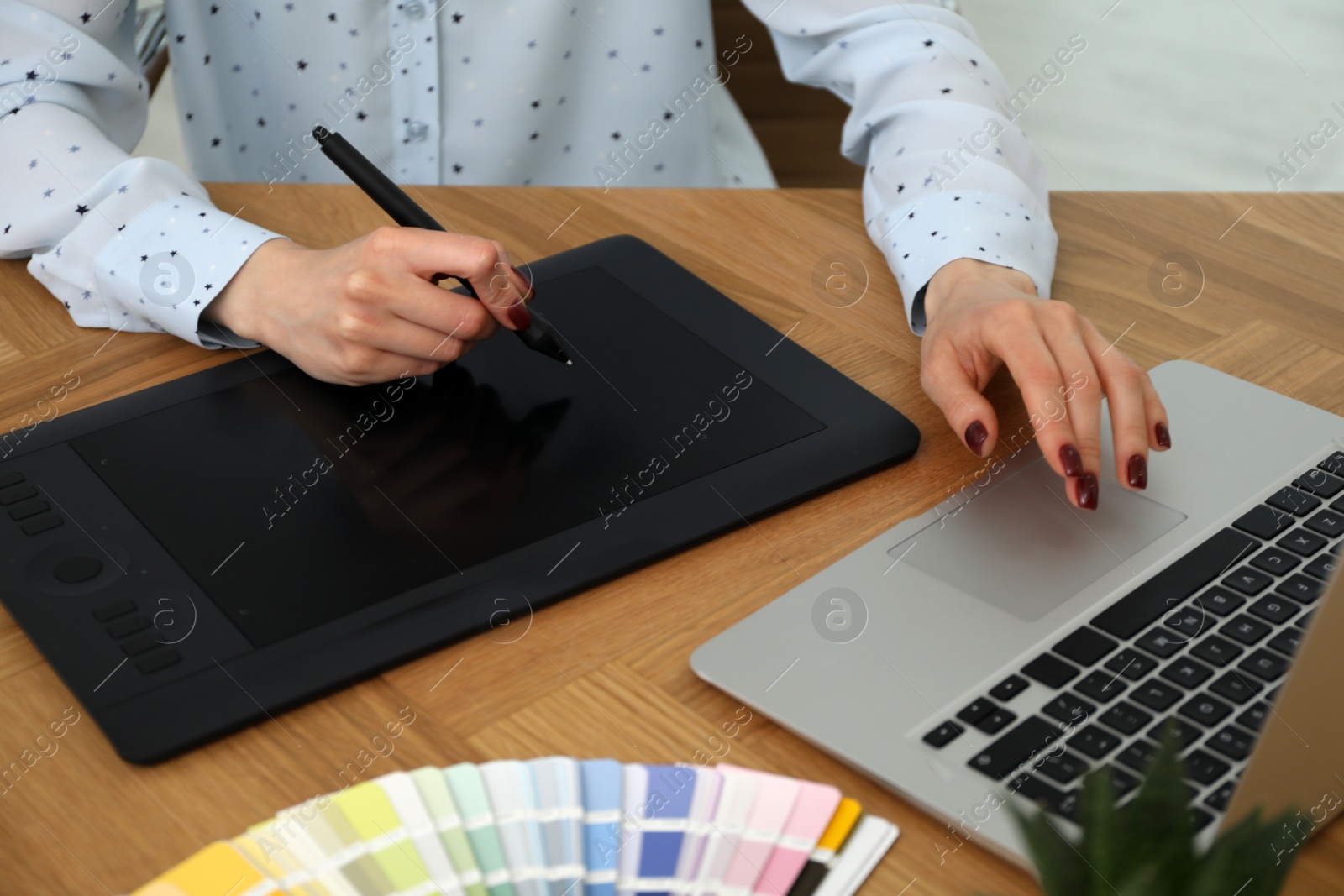 Photo of Professional designer with graphic tablet at wooden table, closeup