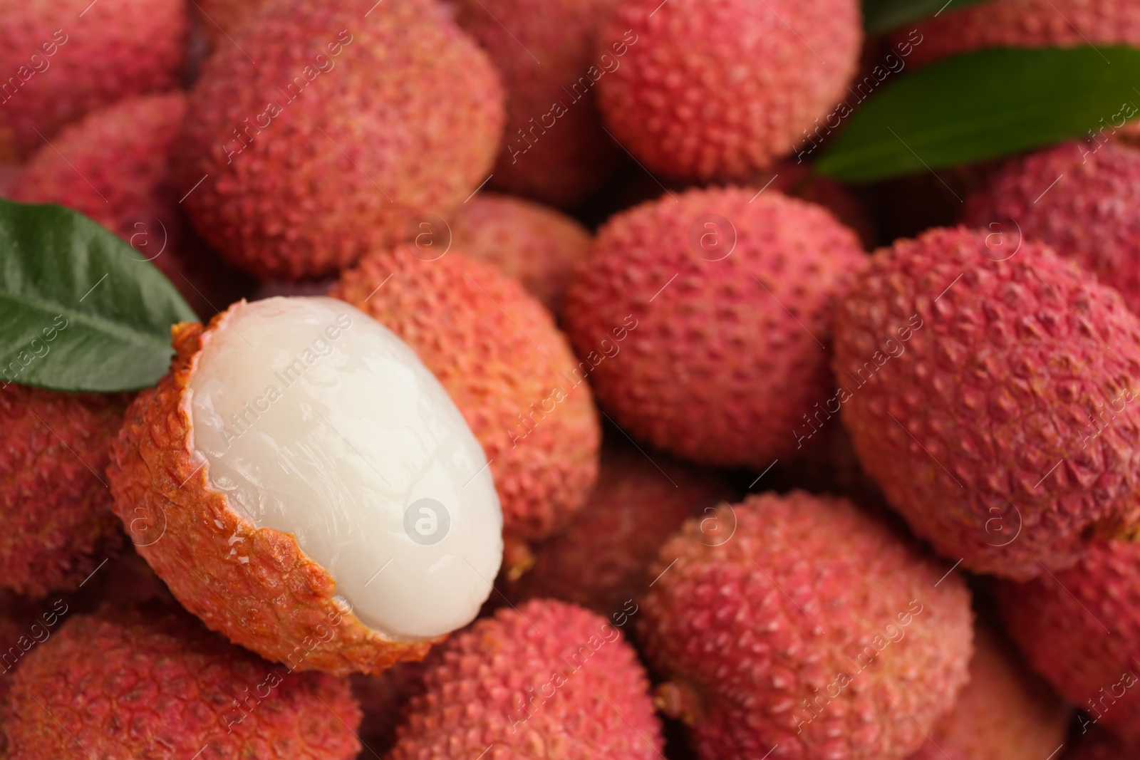 Photo of Pile of fresh ripe lychees with leaves as background, closeup