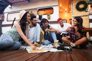 Photo of Young travelers with world map planning trip near motorhome