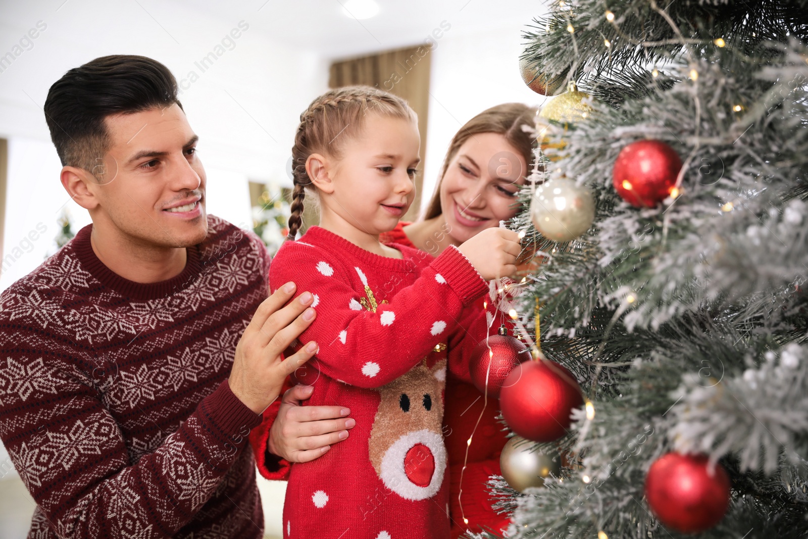 Photo of Happy family with cute child decorating Christmas tree together at home