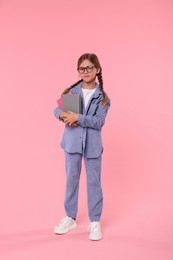 Photo of Cute schoolgirl with books on pink background