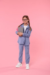 Cute schoolgirl with books on pink background