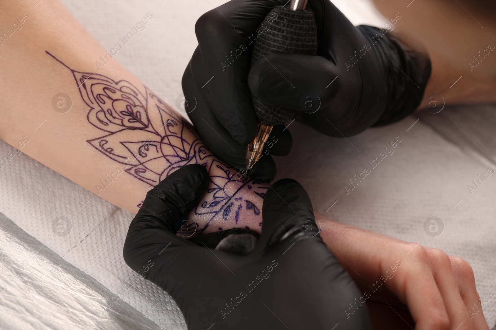 Photo of Professional artist making tattoo on hand at table, closeup