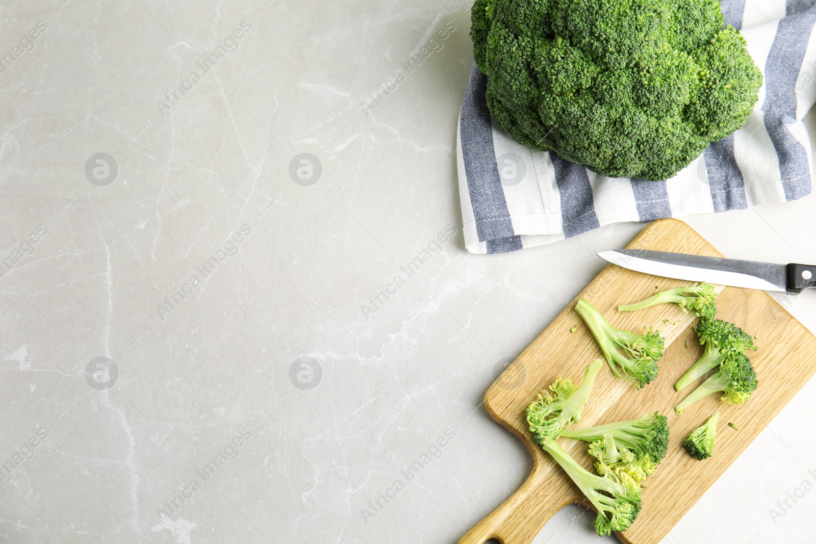 Photo of Raw green broccoli on light grey marble table, flat lay. Space for text