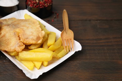 Photo of Delicious fish and chips served on wooden table, closeup. Space for text