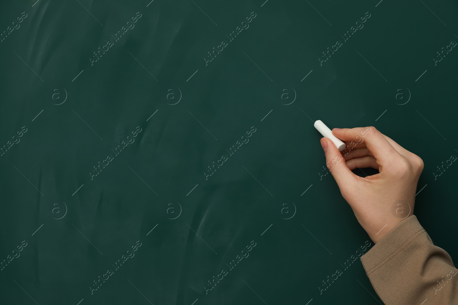 Photo of Woman with white chalk near green board, closeup. Space for text