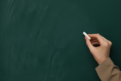 Woman with white chalk near green board, closeup. Space for text