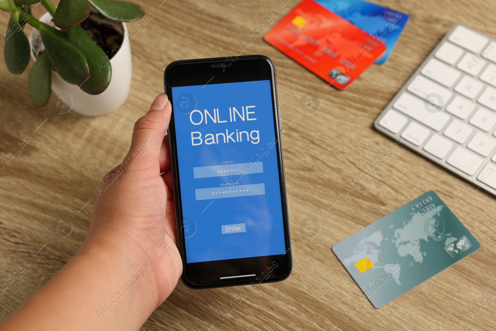 Photo of Woman using smartphone with online banking application at wooden table, top view