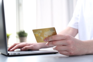 Photo of Online payment. Woman with laptop and credit card at white table, closeup