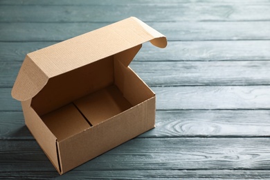 Photo of Open cardboard box on dark wooden table. Space for text