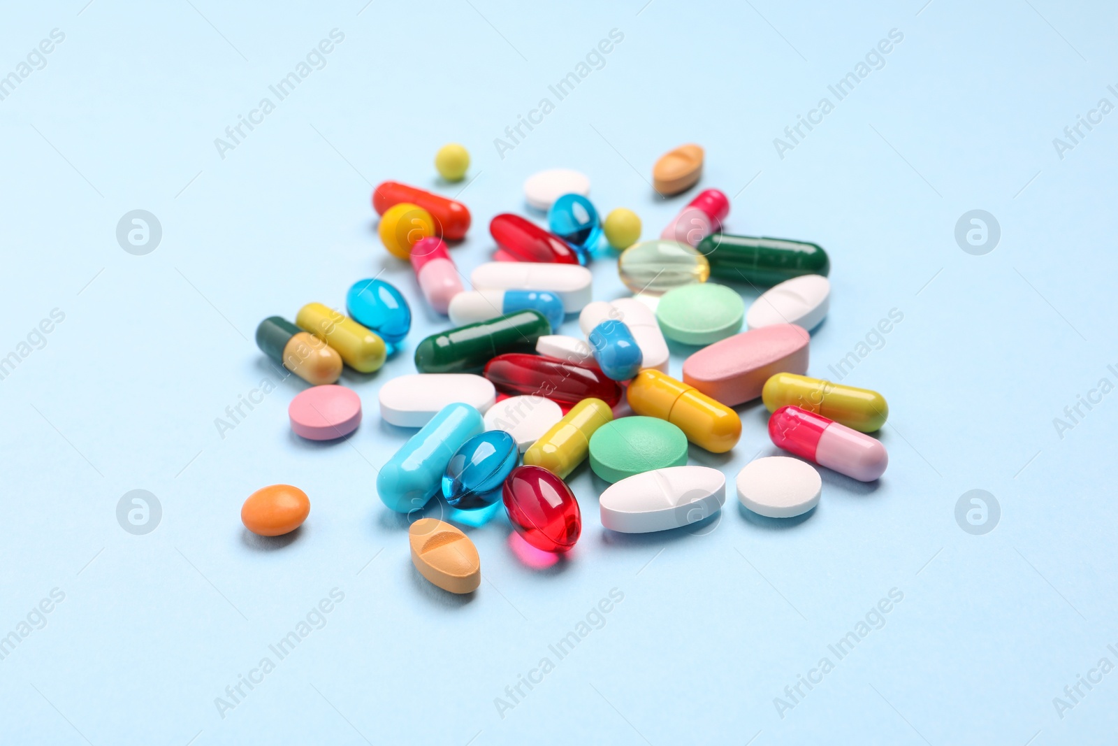 Photo of Many different pills on light blue background