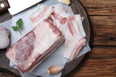 Photo of Tasty salt pork with garlic and parsley on wooden table, top view