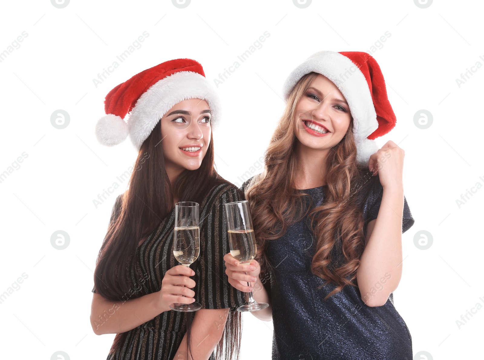 Photo of Beautiful young women in Santa hats with glasses of champagne on white background. Christmas celebration