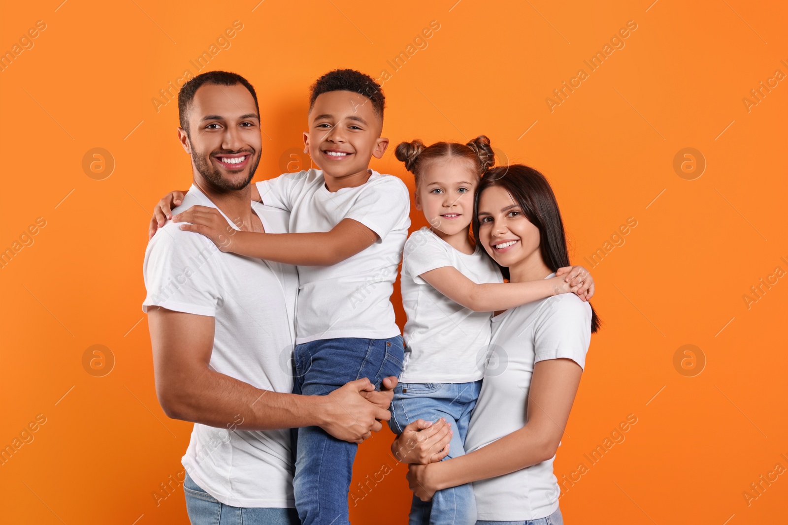 Photo of Happy international family with children on orange background