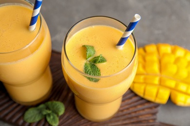 Photo of Glasses of fresh mango drink and fruit on table, closeup