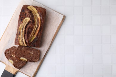 Delicious banana bread on white tiled table, top view. Space for text
