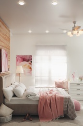 Photo of Stylish bedroom interior with modern ceiling fan and pictures