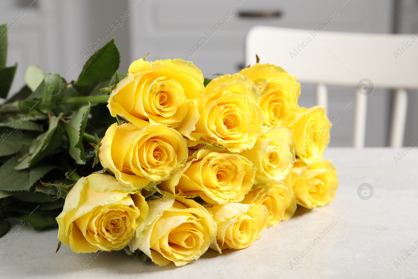 Photo of Beautiful bouquet of yellow roses on light grey table indoors, closeup