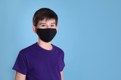 Photo of Boy wearing protective mask on light blue background, space for text. Child safety