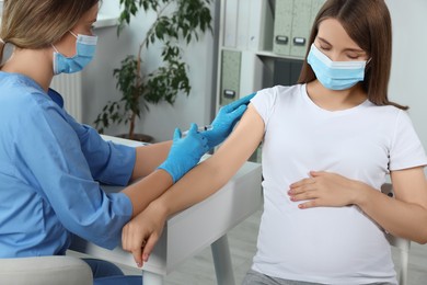 Doctor giving injection to pregnant woman in hospital