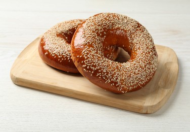 Photo of Delicious fresh bagels with sesame seeds on white wooden table