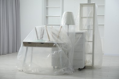 Photo of Modern furniture covered with plastic film at home